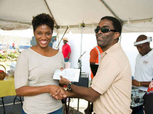Arawak’s Erwin Jones presents winning customer, Mrs. S. Lashley with her Staycation prize for two at the Almond Beach Hotel.